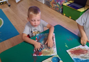 Chłopiec maluje palcami nt. dowolny.